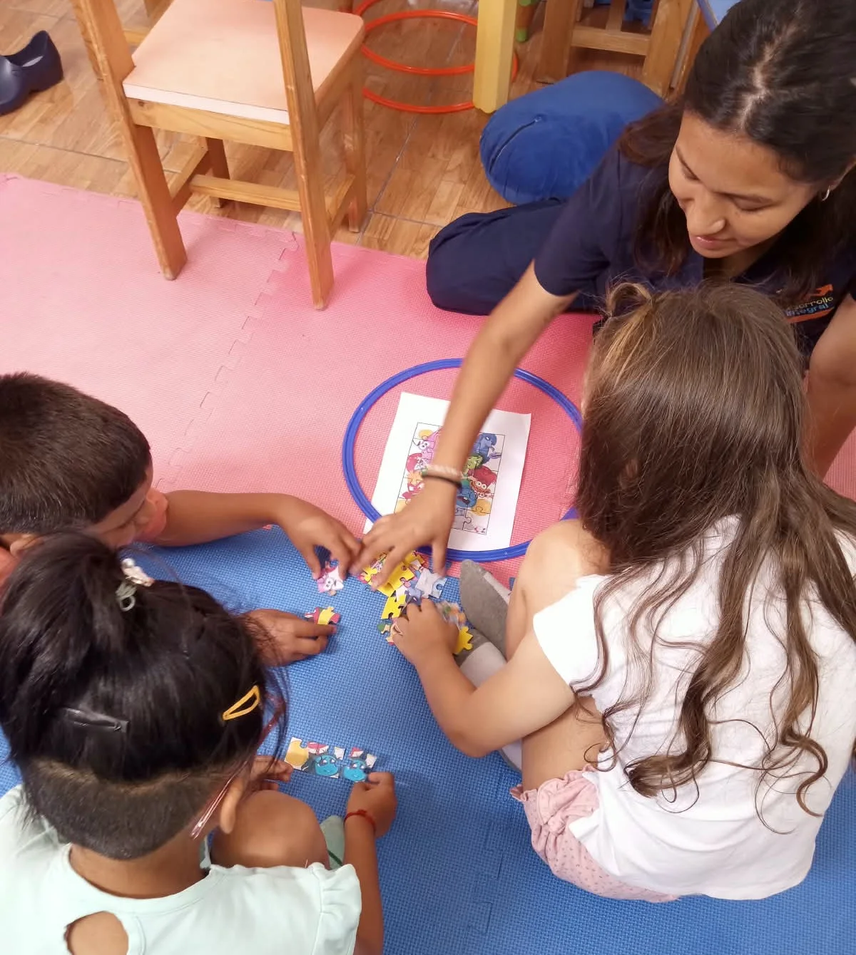 Cuatro niños arman un rompecabezas por turnos con la terapeuta, en una sesión del programa